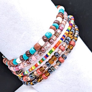 May include: A set of six colorful beaded bracelets with a variety of colors including turquoise, brown, pink, orange, yellow, and black.