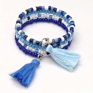 May include: A multi-strand beaded bracelet with blue, white, and black beads. The bracelet has two blue tassels attached to it.