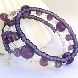 May include: A purple and clear beaded bracelet with a silver clasp. The bracelet is made with amethyst and clear glass beads.