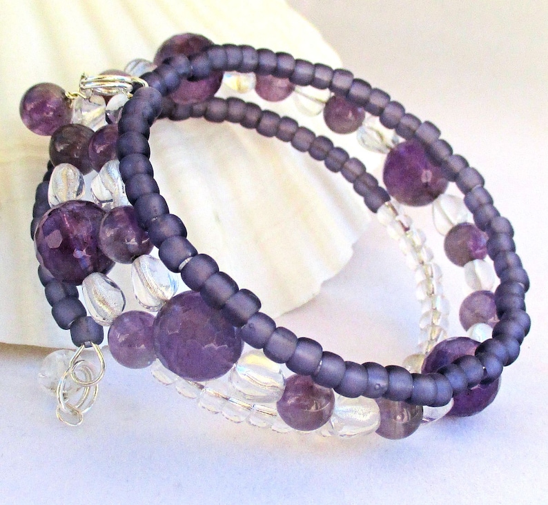 May include: A purple and clear beaded bracelet with a silver clasp. The bracelet is made with amethyst and clear glass beads.