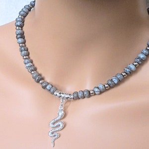 May include: A grey and white stone bead necklace with a silver snake pendant.