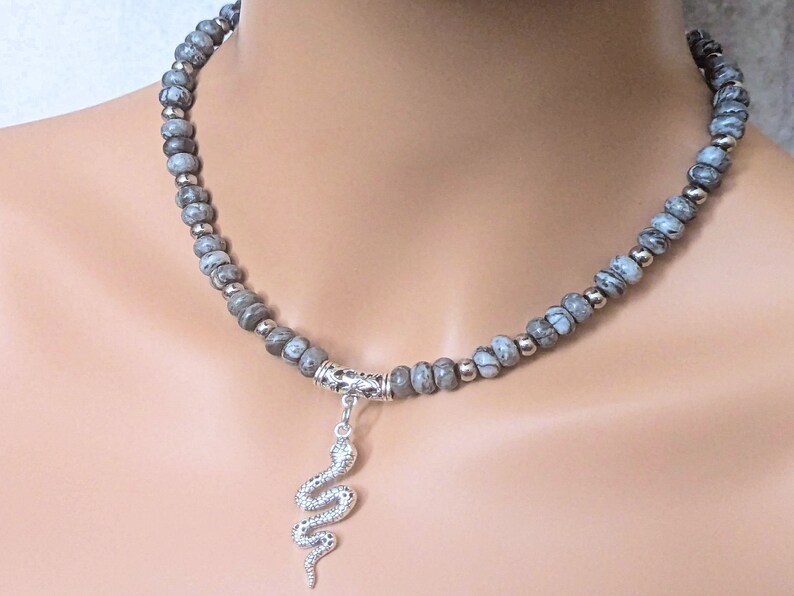 May include: A grey and white stone bead necklace with a silver snake pendant.