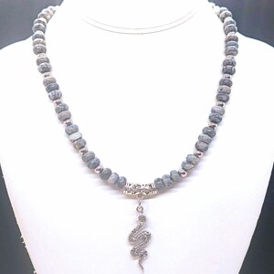 May include: A grey and silver beaded necklace with a silver snake pendant.