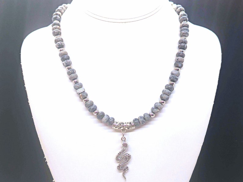 May include: A grey and silver beaded necklace with a silver snake pendant.