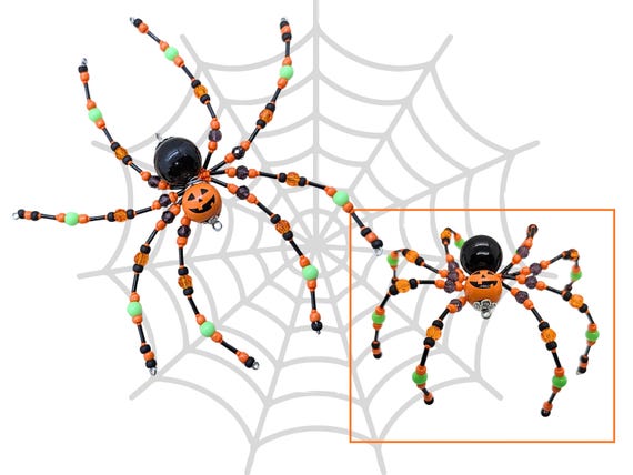 Hand-beaded jack-o'-lantern spider ornament — tiny, weird, and weirdly lovable Halloween shelf art that someone actually assembled bead by bead.