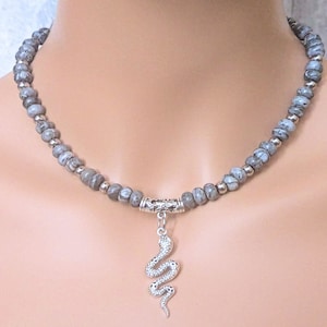 May include: A silver snake pendant necklace with a grey and white stone bead chain.