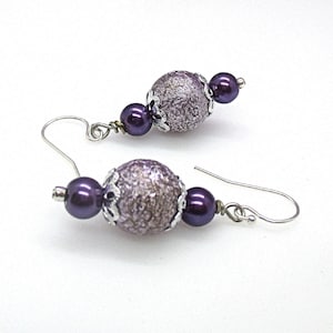 May include: Purple and silver dangle earrings with a textured sphere and a smaller pearl bead.