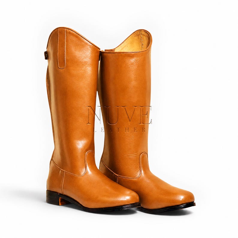 May include: A pair of tall, tan leather riding boots. The boots have a smooth, polished finish and a classic design, with a high shaft and a slight heel. The boots are displayed against a white background.