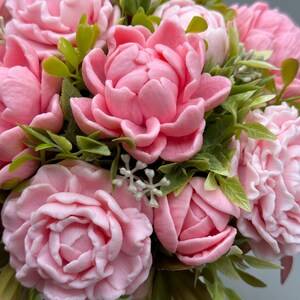 Pode incluir: Um close-up de um buqu&ecirc; de flores de pe&ocirc;nia rosa com folhas verdes. As flores est&atilde;o em plena flora&ccedil;&atilde;o, com p&eacute;talas delicadas e uma cor pastel suave. O arranjo &eacute; exuberante e cheio, com uma variedade de texturas e tons de rosa.
