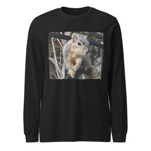 Puede incluir: Camiseta negra de manga larga con una fotografía de una ardilla posada en una barandilla de metal negro. La ardilla tiene pelaje gris y marrón y mira hacia un lado. El fondo está borroso con árboles.
