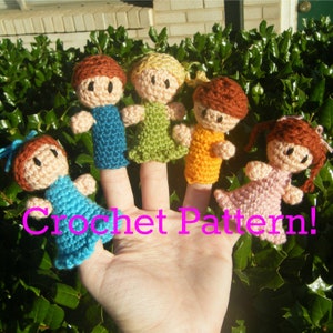May include: Five crocheted finger puppets, each with a different color outfit and hair. The puppets are on a hand, with the text "Crochet Pattern!" below them.