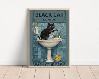 May include: A framed print featuring a black cat washing its paws in a vintage sink. The artwork includes the text "BLACK CAT & SINK CO." above the cat and "WASH YOUR PAWS" below. A yellow rubber ducky sits on the floor.