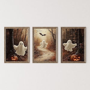 May include: Set of three framed Halloween art prints. Each print features a white ghost in a forest setting with a carved pumpkin and a bat. The artwork has a vintage, autumnal color palette with brown and orange tones.
