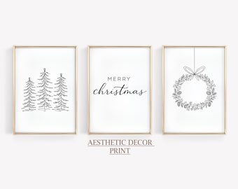 May include: Set of three framed art prints with gold frames. The prints feature black line drawings of Christmas trees, the words "Merry Christmas," and a wreath. The text "Aesthetic Decor Print" is below the middle print.