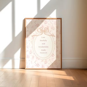 May include: A framed print with a light brown wooden frame. The artwork features a floral pattern in shades of pink and white. The text "I am fearfully and wonderfully made PSALM 139" is displayed in a decorative oval.