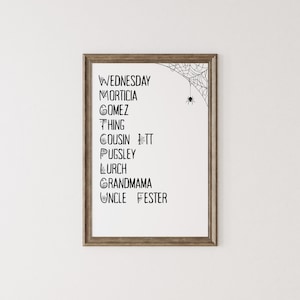 May include: A framed print featuring a list of names from the Addams Family, including Wednesday, Morticia, and Gomez. The names are in black text on a white background, with a spider web and spider graphic in the upper right corner.
