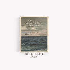 May include: A framed print with a gold border features an ocean scene with a cloudy sky. The text "When you go through deep waters, I will be with you" is written in elegant script. The words "Aesthetic Decor Print" are at the bottom.