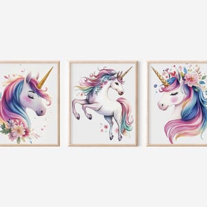May include: Set of three framed unicorn art prints. Each print features a watercolor illustration of a unicorn with a golden horn and a flowing mane in shades of pink, blue, and purple. Floral accents complete the whimsical design.