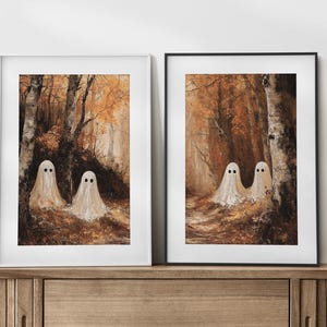 Op de afbeelding: Twee ingelijste kunstdrukken met een bossc&egrave;ne met drie witte spookfiguren. Het kunstwerk heeft een warm kleurenpalet van bruin, oranje en geel, waardoor een spookachtige maar uitnodigende sfeer ontstaat. De geesten hebben zwarte stipogen.