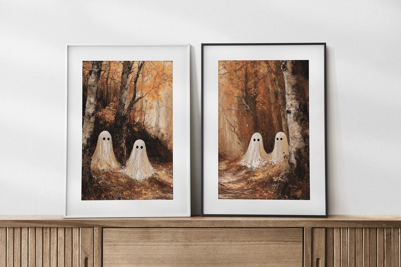 Op de afbeelding: Twee ingelijste kunstdrukken met een bossc&egrave;ne met drie witte spookfiguren. Het kunstwerk heeft een warm kleurenpalet van bruin, oranje en geel, waardoor een spookachtige maar uitnodigende sfeer ontstaat. De geesten hebben zwarte stipogen.