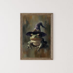 May include: A framed print of a frog wearing a purple witch's hat. The frog has large eyes and is set against a blurred, earthy background. The artwork has a painterly style, with soft details and a touch of fantasy. The frame is brown.