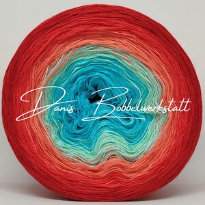 Könnte beinhalten: Ein lebendiger Wollknäuel mit einem Farbverlauf von Rot zu Koralle, Türkis und Türkisblau. Das Garn ist eng gewickelt und zeigt die verschiedenen Farbabstufungen. Der Text "Danis Bobbelwerkstatt" ist in einer Schreibschrift über die Mitte des Garns geschrieben.