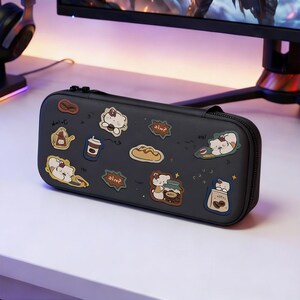 May include: Black zippered case decorated with cartoon stickers of a bear, bread, coffee, and other food items. The case is rectangular and has a black zipper closure.