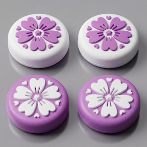 Peut inclure: Quatre objets ronds et décoratifs avec un motif floral. Deux sont blancs avec des fleurs violettes, et deux sont violets avec des fleurs blanches. Chaque fleur a des pétales en forme de cœur et un centre en forme d'étoile.