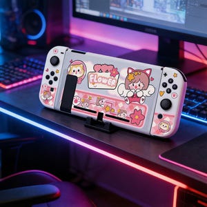 Puede incluir: Una funda blanca y rosa para Nintendo Switch con un diseño floral y de personajes de dibujos animados. La funda presenta la palabra "FLOWER" y varios personajes de dibujos animados. La funda está sobre un soporte negro.