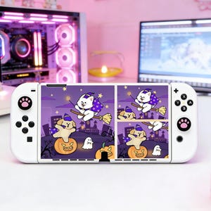 May include: White Nintendo Switch Joy-Cons with a Halloween-themed skin. The skin features a cartoon cat and dog riding brooms, with pumpkins and ghosts against a purple night sky. The controllers have paw print designs.