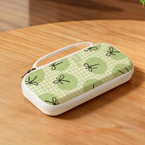 May include: A white rectangular case with a zipper closure and a handle. The case is decorated with a green apple pattern on a light green and white checkered background. The text "Green Apple" is visible on the case.