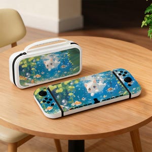 May include: A white Nintendo Switch case and controller with a matching design. The design features a cartoon cat swimming underwater with fish and bubbles. The case has a black zipper and a white handle.