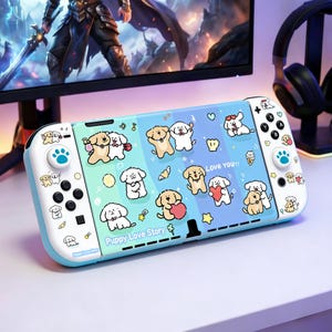 Puede incluir: Una consola Nintendo Switch azul claro y blanca con un diseño de "Puppy Love Story". La consola presenta cachorros de dibujos animados, corazones y estrellas. Los botones y joysticks son blancos y azules.
