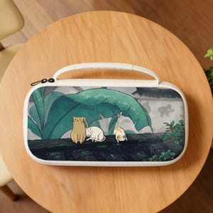 May include: White zippered case with a handle, featuring a whimsical illustration of three cats on a rooftop under large green leaves. The cats are in shades of tan, white, and calico. The background shows a rainy scene.