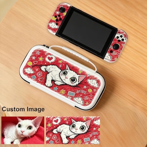 Könnte beinhalten: Eine tragbare Spielkonsole und eine passende weiße Tragetasche mit rotem Hintergrund, verziert mit einer weißen Katzenillustration, Herzen, Wolken und Sternen. Die Konsole hat rote Seiten-Controller mit passenden Katzenmotiven und schwarzen Tasten.