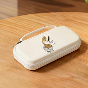 May include: Off-white rectangular case with a zipper closure and a white handle. The case features a cartoon illustration of a cat sitting on a toilet while looking at a phone. The case is on a wooden surface.