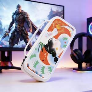 Pode incluir: Uma capa retangular branca para console de jogos com uma ilustração colorida. A capa possui fecho de zíper e uma alça branca. A ilustração inclui uma figura branca, formas laranja e azuis e folhagem verde. Um monitor de jogos e fones de ouvido estão no fundo.