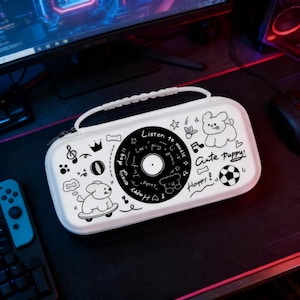 Puede incluir: Estuche de transporte blanco con asa, con gráficos de dibujos animados en blanco y negro de un disco, notas musicales y un cachorro. El texto incluye "Listen to music", "Cute Puppy!" y "Happy!".