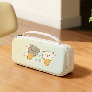 Puede incluir: Estuche rectangular con asa y cremallera blancas. La funda presenta un fondo degradado pastel y una ilustración de dibujos animados de dos gatos en conos de helado. Estrellas de colores rodean los conos.
