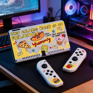 May include: A white and yellow gaming console case with a food-themed design, featuring a hot dog, pizza, and ice cream. The text "THIS CALORIE BOMB IS SO DELICIOUS" is displayed. Two white controllers with food graphics are also visible.
