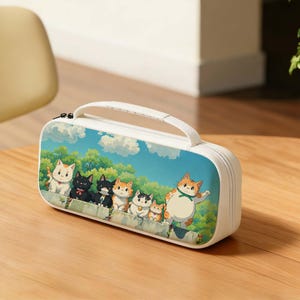 May include: White pencil case featuring a cartoon illustration of several cats against a blue sky and green trees. The cats are in various colors, including orange, black, and white. The case has a white handle and zipper.