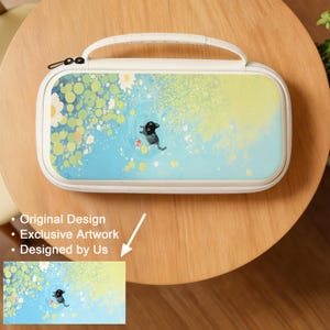 May include: A cream-colored carrying case with a whimsical illustration of a black creature swimming in a pond with fish. The case has a white handle and a zipper closure. The artwork is set against a blue and yellow background.