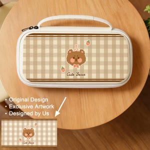 May include: A cream-colored pencil case with a brown and tan plaid pattern. The case features a cartoon bear with a party hat and the text "Cute Bear." The case has a white handle and a black zipper.