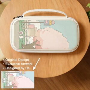 May include: A cream-colored carrying case with a whimsical illustration of a tree with pink blossoms, a retro television, and sheep. The case has a white handle and zipper, and the design is set against a light blue background.