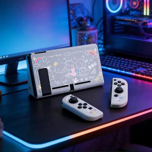 Puede incluir: Una funda y mandos de consola Nintendo Switch grises con un diseño lúdico con temática de perros. La funda presenta una ilustración de dibujos animados de perros, arcoíris y notas musicales. Los mandos son de color gris claro con botones negros y detalles de huellas de patas.