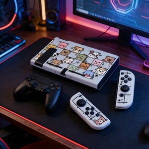 Puede incluir: Una consola de juegos con una cubierta gris claro con una cuadrícula de caras de animales de dibujos animados. También se ve un controlador negro y dos controladores blancos con diseños de animales a juego, todo sobre una superficie negra.