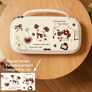 Peut inclure: Une trousse de transport rectangulaire couleur crème avec une poignée supérieure et une fermeture éclair. La surface présente des illustrations de deux chiots, des nœuds rouges, des fraises, des cœurs et le texte "Laughter is poison to tear" et "I'll think of you every step of the way."