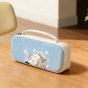 May include: A white and light blue pencil case with a handle. The case features a cartoon illustration of two characters with bubbles and hearts. The text "Mashi Maro" is printed on the case.