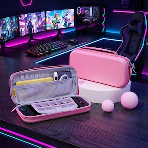 May include: A pink gaming console carry case with a zip closure, handle, and internal storage. The case is open, showing a console and accessories. Two pink spheres are in the foreground. A gaming setup with monitors and a keyboard is in the background.