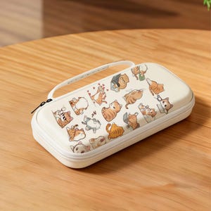 May include: Off-white, rectangular case with a white zipper and handle. The case is covered in cartoon illustrations of various cats in different poses. The cats are primarily orange and white, with some gray and brown accents.